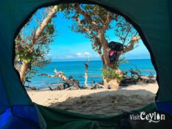 View of the beach from inside a tent – Photo by Sameera Marapperuma View of the beach from inside a tent, with sandy shore and calm ocean waters.